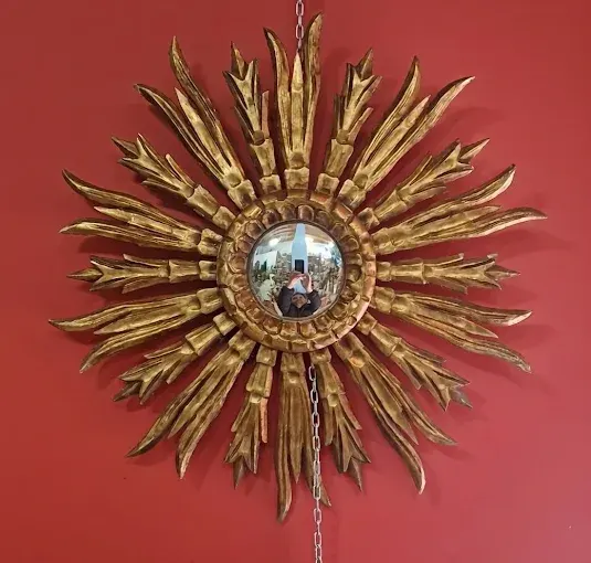 Espejo sol de madera dorada colgado en la tienda de antigüedades